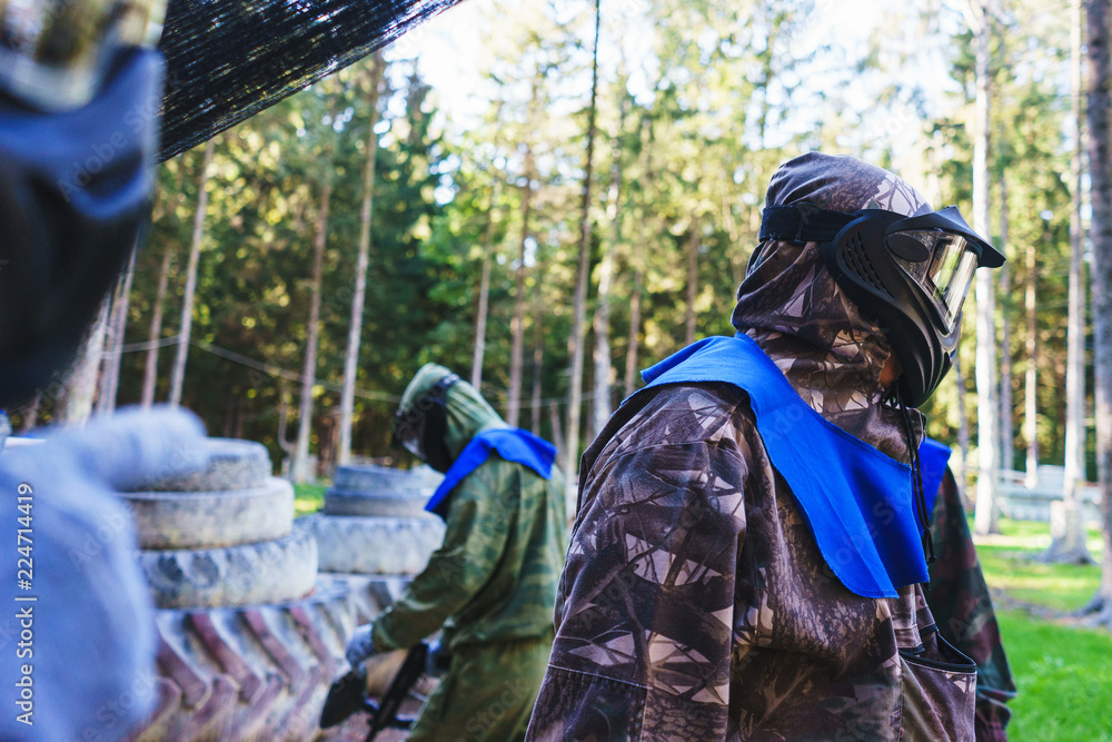 Players in special equipment and protective masks, with game markers participate in the game-simulator paintball.