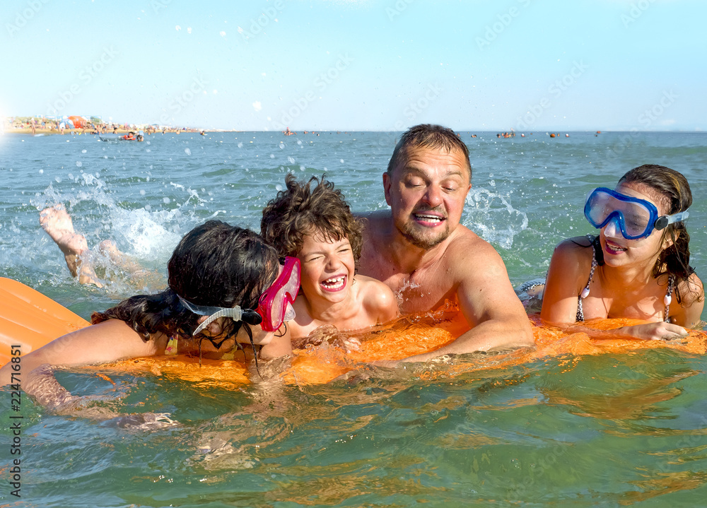 Happy family playing in the ocean and splashing water - Tourists on vacation on a tropical island Happy family playing in the ocean and splashing water - Tourists on vacation on a tropical island