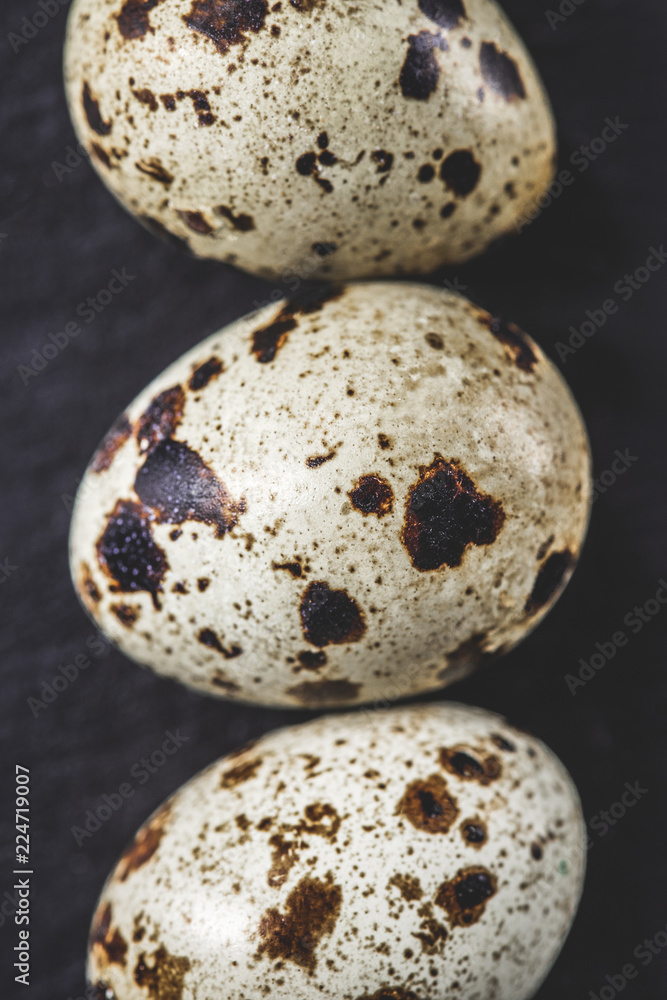 Obraz premium top view of organic unshelled quail eggs on black, close-up view
