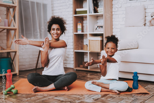 Mother and young daughter doing yoga together at home