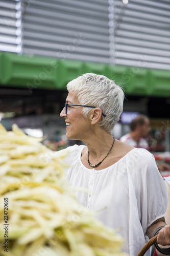Senior woman buying fresh organic vegetable on market