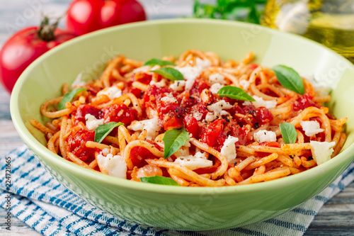 Spaghetti pasta with tomato sauce, mozzarella cheese and fresh basil leaves on white-blue vintage wooden background. Selective focus.