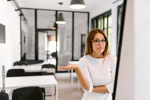 Portrait of a puzzled young business woman looking at white board.