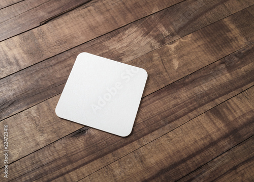 Blank square beer coaster on wooden background. photo