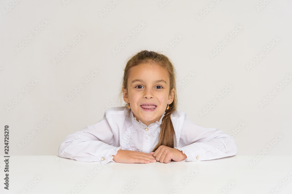 Portrait of a cute baby girl on a white background at the table. Portrait of a cute baby girl on a white background at the table.