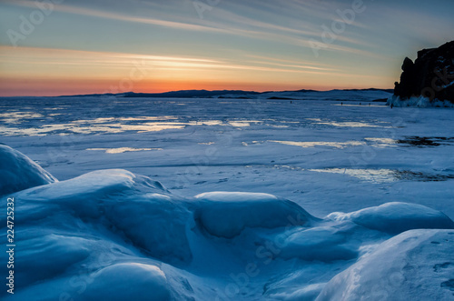 Walking in winter on the ice and snow texture. Sunset and silhouettes of people