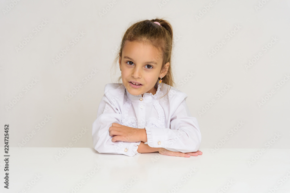 Portrait of a cute baby girl on a white background at the table. Portrait of a cute baby girl on a white background at the table.