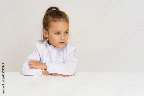 Portrait of a cute baby girl on a white background at the table.