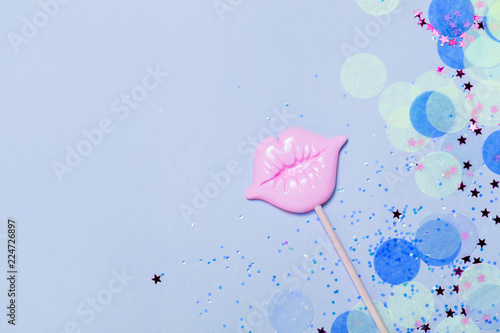 Creative blue confetti background with pink lips. Top view photo