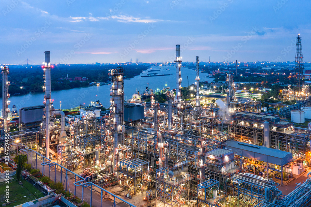 Obraz premium Industrial view at oil refinery plant form industry zone with sunrise and cloudy sky.Oil refinery and Petrochemical plant at dusk,Thailand. Aerial view
