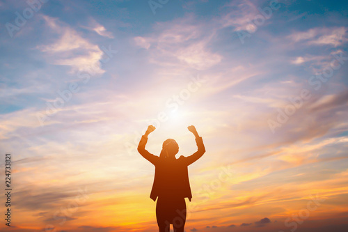 Silhouette successful businesswoman. Hold hands over the head with joy at sunset.