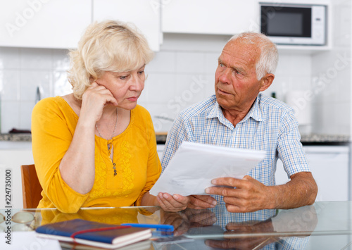 Worried mature couple with documents disscusing in home photo