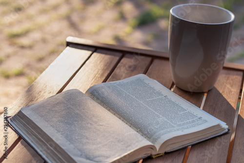 Christian worship and praise. The open bible on a chair in the morning light with cup of coffee. photo