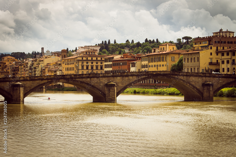 Obraz premium Panoramic view of the city of Florence. Storm clouds cover the sky. A small rowing boat circulates in the river.