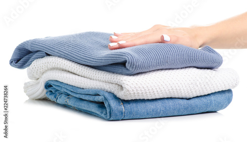 Stack of clothing jeans sweaters in hand on a white background isolation