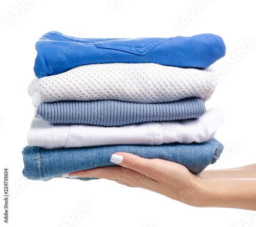 Stack of clothing jeans sweaters in hand on a white background isolation