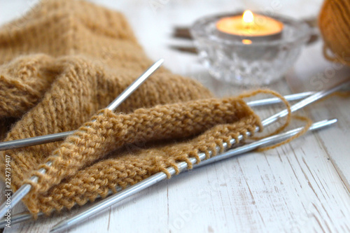 Knitting a sock, brown. The candle is burning. Rest, autumn mood. The concept of retirement age and quiet old age.