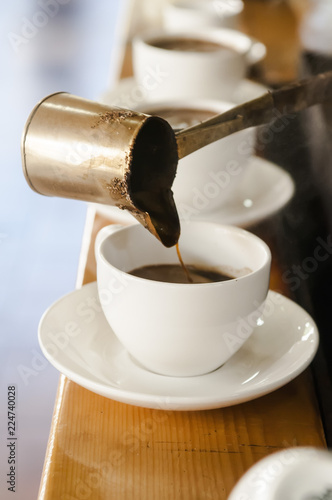 three cups of coffee, man pours coffee from cezve, concrete background