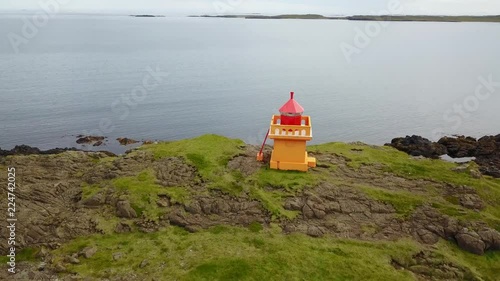 Eastern Icelandic drone shot of small rock pile and lighthouse near coast