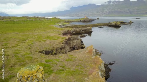 Eastern Icelandic drone shot of small rock pile and lighthouse near coast