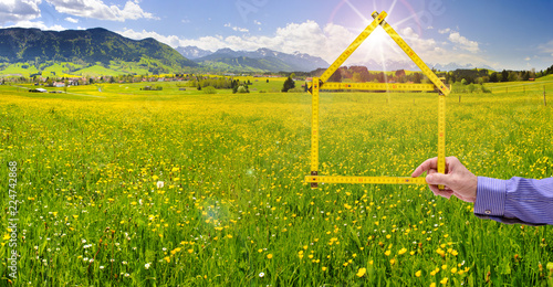 Makler hält Meterstab in Form von einem Haus als Symbol für Wohnen im Grünen photo