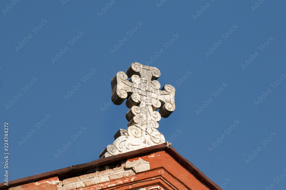 stone Gothic cross on the roof, against the blue sky