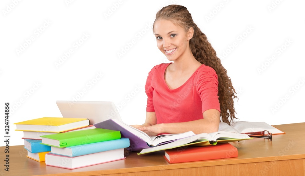 Friendly Girl Sitting Behind a Desk with a Books and Using Friendly Girl Sitting Behind a Desk with a Books and Using