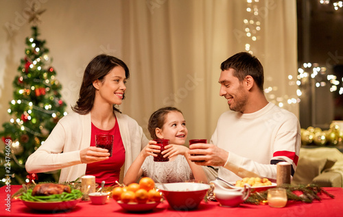 holidays  family and celebration concept - happy mother  father and little daughter having christmas dinner at home