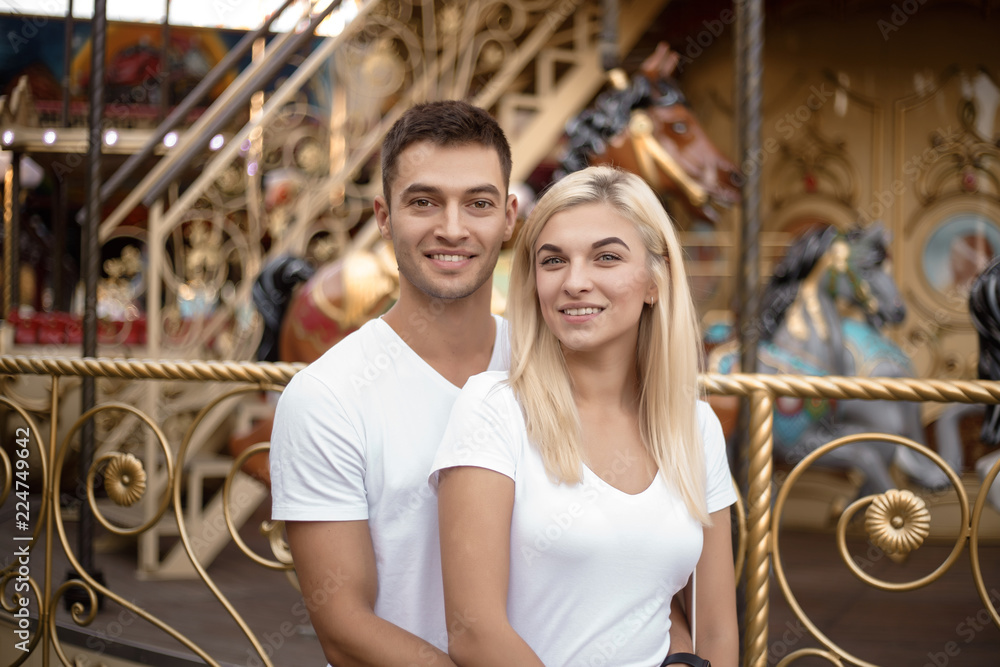 Cheerful loving couple walking outdoors in the amusement park posing.