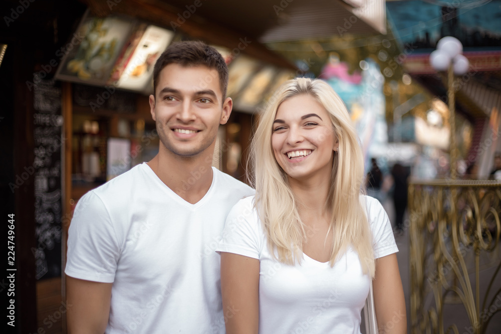 Cheerful loving couple walking outdoors in the amusement park posing.