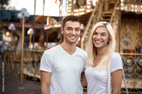 Cheerful loving couple walking outdoors in the amusement park posing.