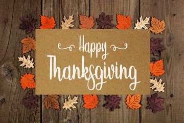 Happy Thanksgiving greeting card with frame of wooden autumn leaves over a rustic wood background
