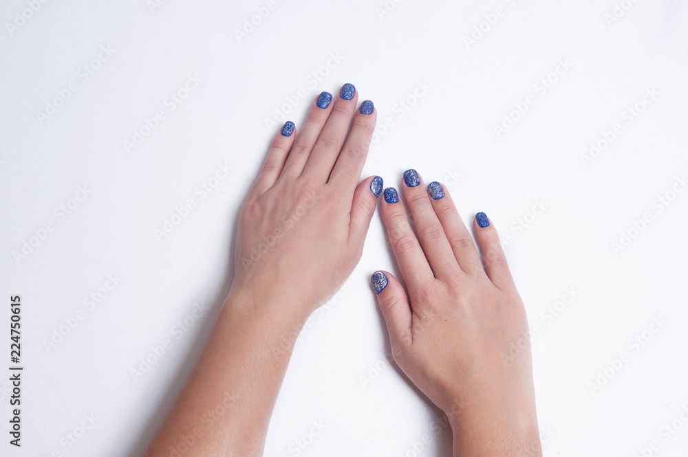 Naklejka premium Stylish trendy blue festive women's manicure with silver sequins. Beautiful hands of young woman isolated on white background. Place for text.