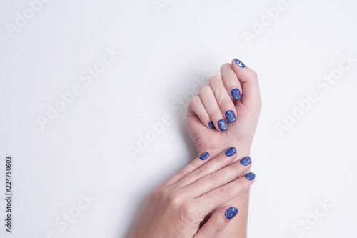 Stylish trendy blue festive women's manicure with silver sequins. Beautiful hands of young woman isolated on white background. Place for text.