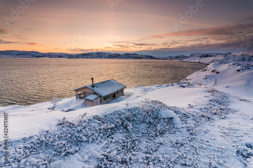 Cottage on the shore of the Arctic Ocean at sunset in winter photo