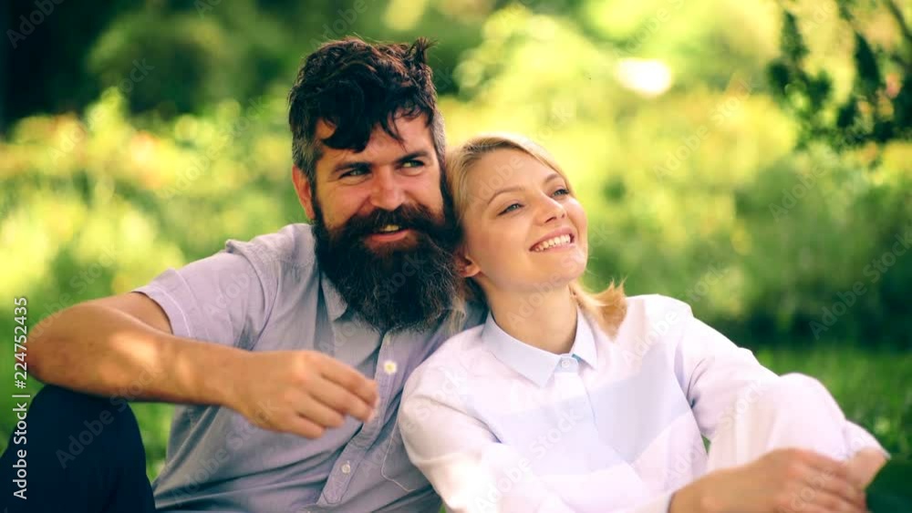 Loving couple hugging in the park. The girl and the bearded guy spend their time sitting in the park on the grass. The concept of relaxation in the park. Loving couple hugging in the park. The girl and the bearded guy spend their time sitting in the park on the grass. The concept of relaxation in the park.