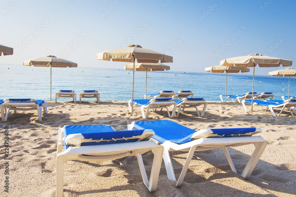 Loungers on a tropical beach. Sun beds and umbrellas on a sandy beach. Summer vacation at the sea