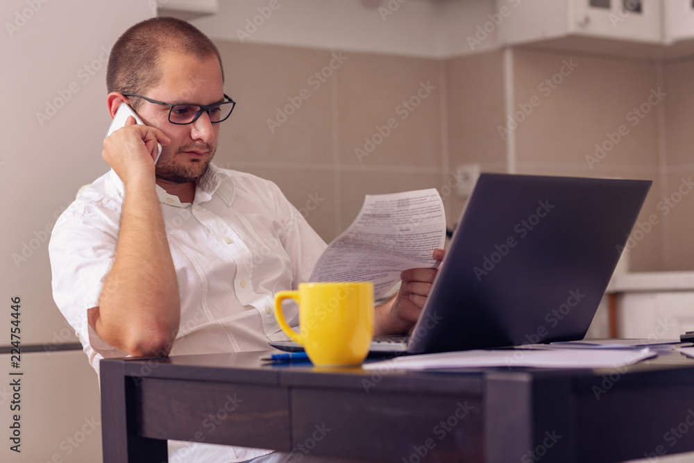 man working with computer while talking on phone at home. man working with computer while talking on phone at home.