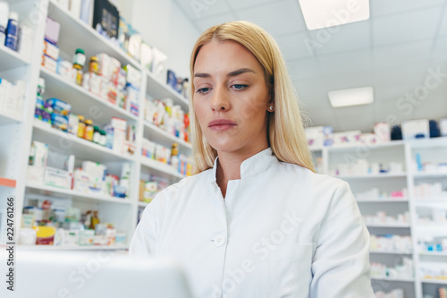 Free Download Beautiful young woman pharmacist at work looking at computer at pharmacy drugstore - GFXLoad
