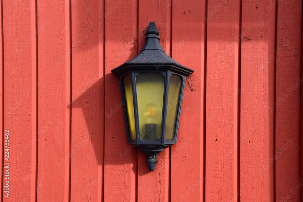 Street lamp on a red wooden wall.
