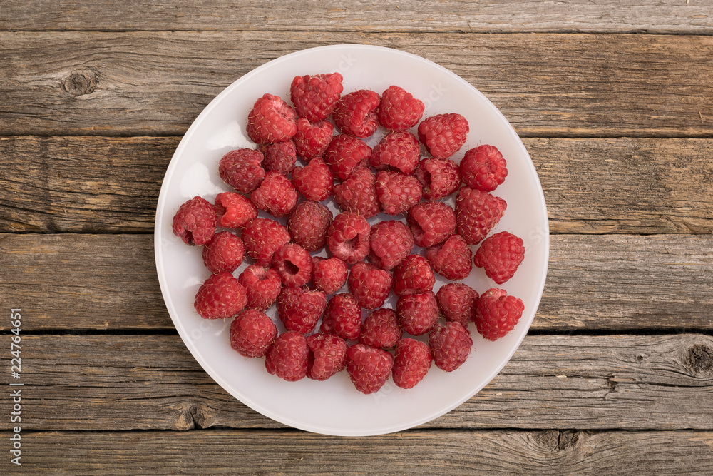 Plate with raspberry on wooden table Plate with raspberry on wooden table