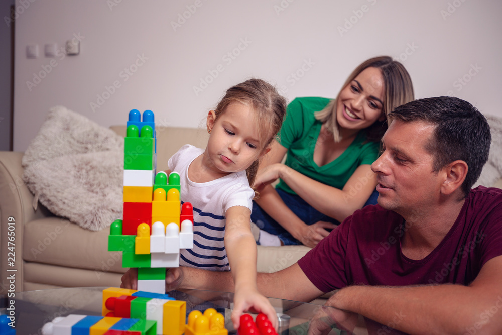 Playing family- mother and father playing with cute daughter cubes together at home. Playing family- mother and father playing with cute daughter cubes together at home.
