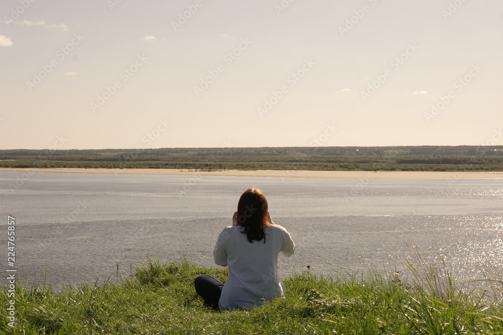 девушка сидит на склоне у реки