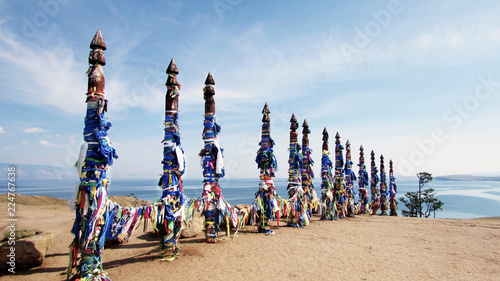 Vivid colored ribbons Hadak tied on posts of wish. Wooden ritual pillars. Sacred place of Buddhist shamans, Baikal, Russia. Mystical traditions of Asia. photo