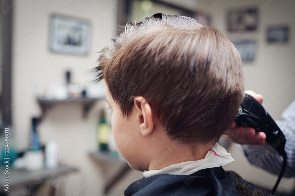 Hairdresser making a haircut to a boy with clipper. Hairdresser making a haircut to a boy with clipper.