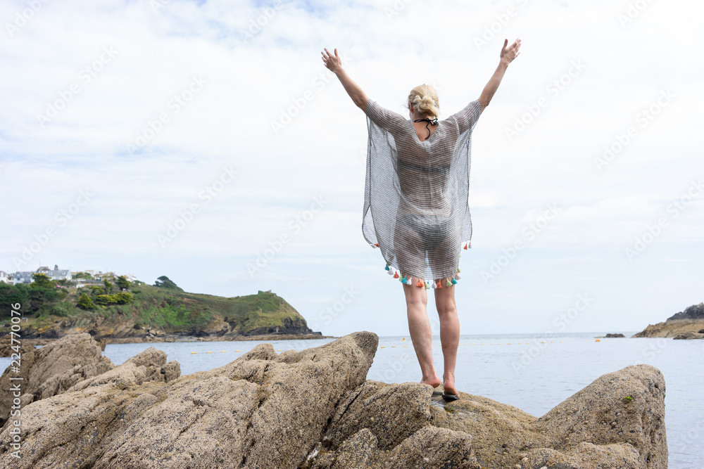 Woman standing on rocks with arms and hands pushed to the sky Woman standing on rocks with arms and hands pushed to the sky