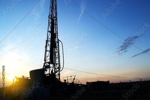 drilling rig drills a well to extract water at sunset in the rays of the setting sun. Water supply of the population