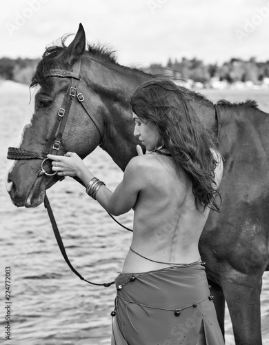 horse and young beautiful naked Amazon woman on river shore