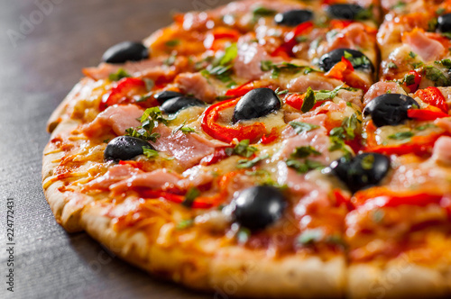 slices of Pizza with Mozzarella cheese, ham, pepper, meat, Tomatoes, olives, Spices and Fresh Basil. Italian pizza on wooden background