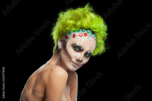 Halloween. Portrait of young beautiful girl with make-up skeleton on her face. And green hair. Isolated on black background. © satyrenko